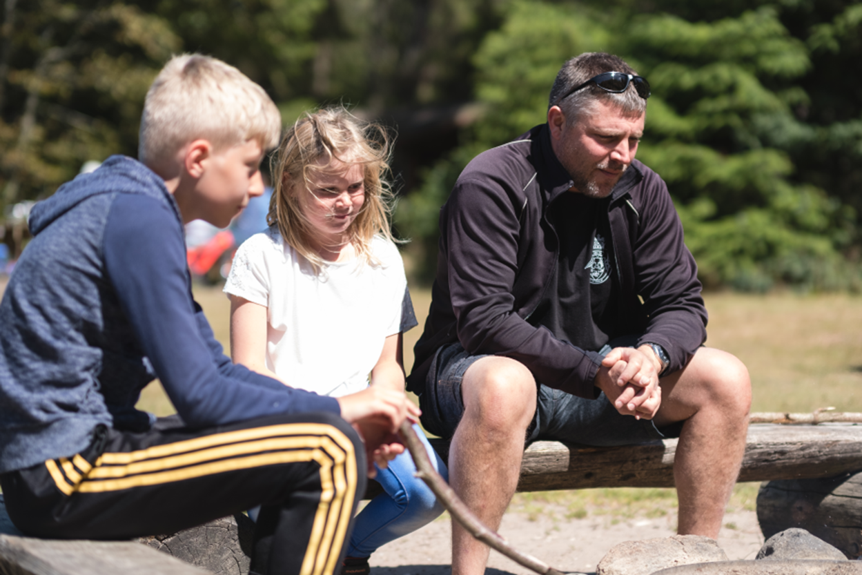 Familie slapper af ved bålpladsen