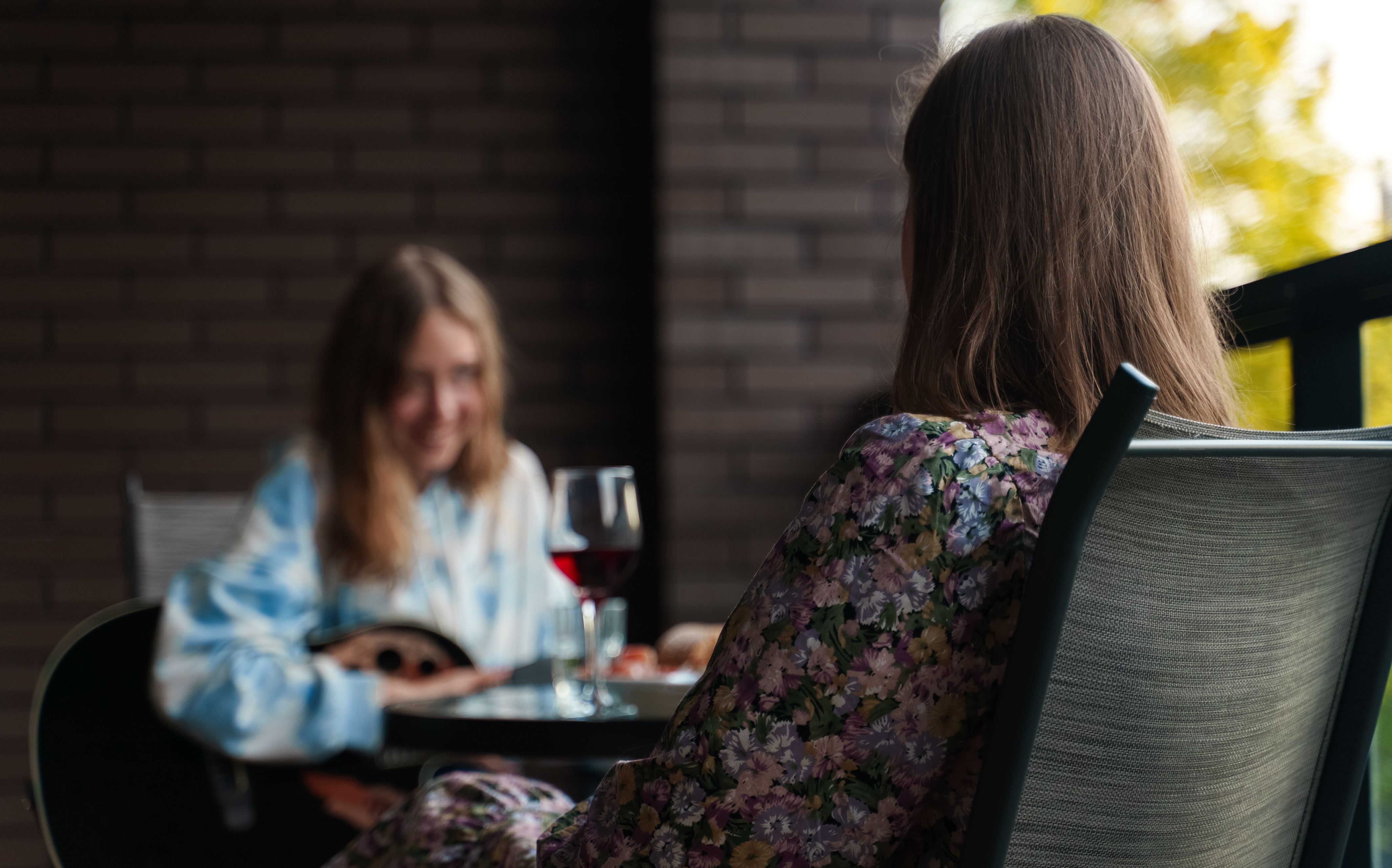 To personer sidder ved cafébord med et glas vin